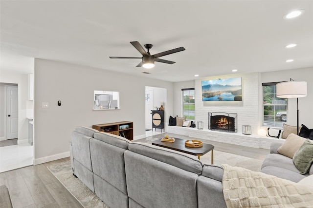 348 Thompson St, Fort Worth, TX 76134 - living room featuring light wood finished floors, recessed lighting, ceiling fan, a brick fireplace, and plenty of natural light