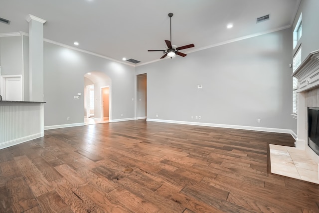 305 Wood Duck Ln, Mckinney, TX 75072 - unfurnished living room with ceiling fan, arched walkways, a fireplace, crown molding, and dark wood-style flooring