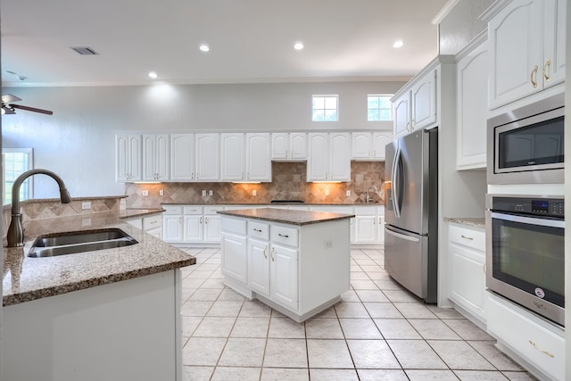 305 Wood Duck Ln, Mckinney, TX 75072 - kitchen featuring stainless steel appliances, a center island, decorative backsplash, light tile patterned floors, and crown molding
