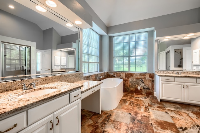 305 Wood Duck Ln, Mckinney, TX 75072 - bathroom featuring vaulted ceiling, a freestanding bath, two vanities, and plenty of natural light