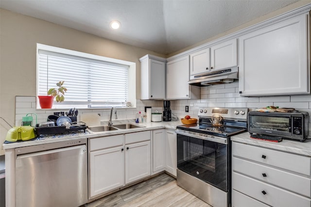 212 Valley Spring Dr, Arlington, TX 76018 - kitchen with stainless steel appliances, under cabinet range hood, tasteful backsplash, light countertops, and light wood-type flooring