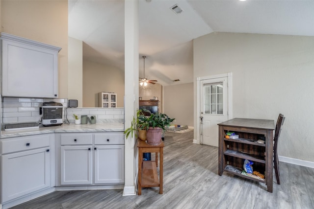 212 Valley Spring Dr, Arlington, TX 76018 - kitchen with lofted ceiling, backsplash, light wood-style flooring, a ceiling fan, and light stone countertops