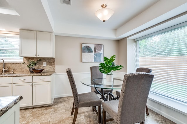 8688 Grenadier Ct, Dallas, TX 75238 - dining space with healthy amount of natural light, a tray ceiling, and light stone finish flooring