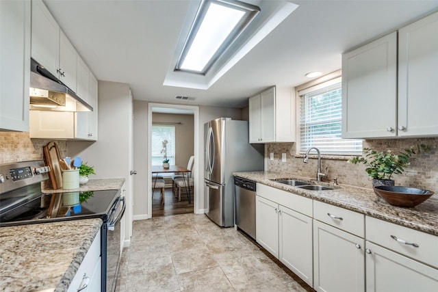8688 Grenadier Ct, Dallas, TX 75238 - kitchen with stainless steel appliances, under cabinet range hood, white cabinetry, tasteful backsplash, and light stone counters