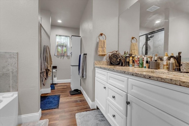 311 W Oak St, Whitewright, TX 75491 - bathroom featuring vanity, a stall shower, wood finished floors, and a garden tub