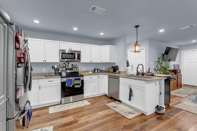 311 W Oak St, Whitewright, TX 75491 - kitchen with stainless steel appliances, a peninsula, white cabinets, recessed lighting, and light stone countertops