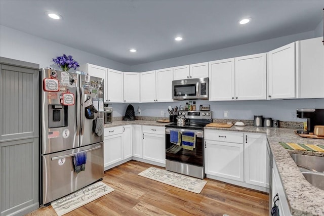 311 W Oak St, Whitewright, TX 75491 - kitchen featuring appliances with stainless steel finishes, white cabinets, light wood-type flooring, recessed lighting, and light stone countertops