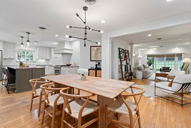 7845 Blackbird Ln, Dallas, TX 75238 - dining space with light wood-style floors, ornate columns, recessed lighting, and a chandelier