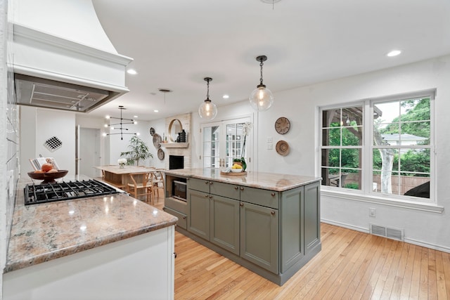 7845 Blackbird Ln, Dallas, TX 75238 - kitchen featuring gray cabinets, light wood-type flooring, light stone countertops, gas cooktop, and pendant lighting