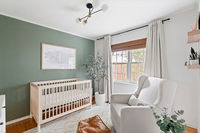 7845 Blackbird Ln, Dallas, TX 75238 - bedroom featuring a chandelier, a crib, and wood finished floors