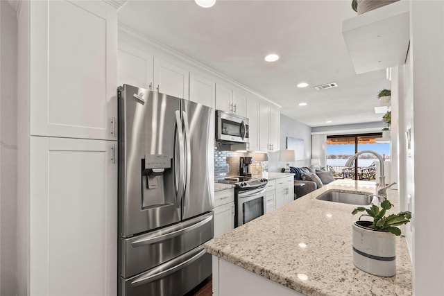 849 S Gun Barrel Ln Unit D6, Gun Barrel City, TX 75156 - kitchen with appliances with stainless steel finishes, open floor plan, white cabinets, backsplash, and light stone countertops