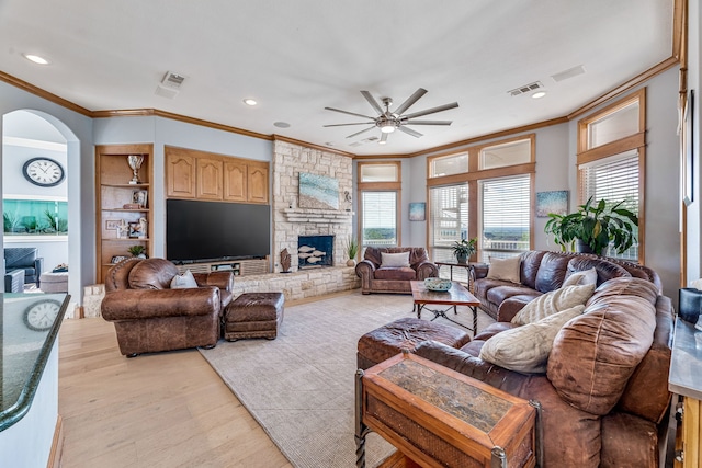 8800 Summit Point Ct, Fort Worth, TX 76179 - living area featuring a ceiling fan, crown molding, arched walkways, light wood finished floors, and a stone fireplace