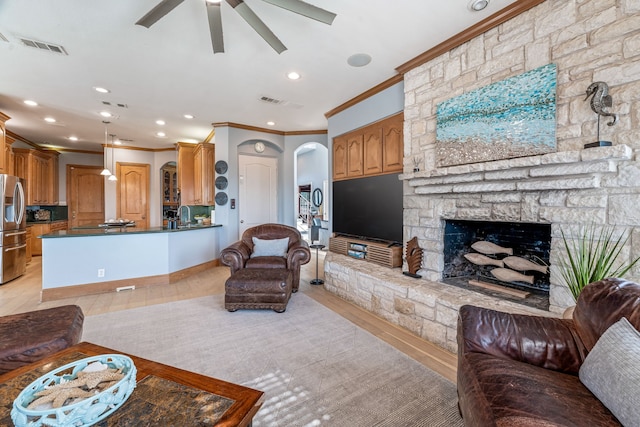 8800 Summit Point Ct, Fort Worth, TX 76179 - living area featuring crown molding, arched walkways, ceiling fan, a stone fireplace, and recessed lighting