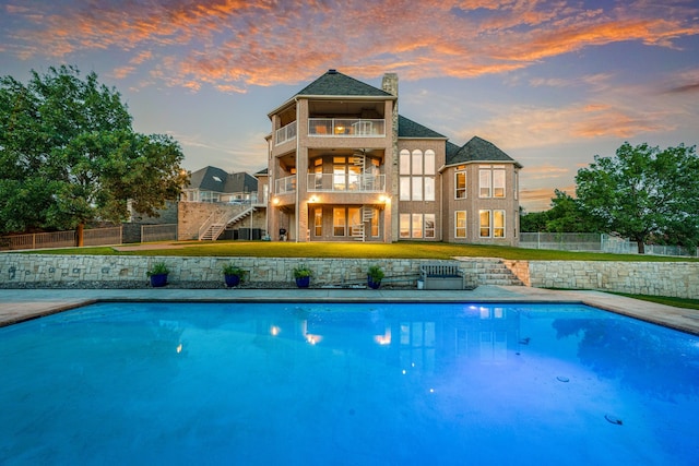 8800 Summit Point Ct, Fort Worth, TX 76179 - back of house at dusk with a balcony, stairs, a fenced backyard, and a chimney