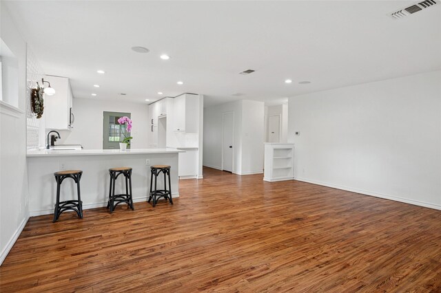 522 Carol Ct, Richardson, TX 75081 - kitchen featuring wood finished floors, white cabinetry, a kitchen breakfast bar, light countertops, and recessed lighting