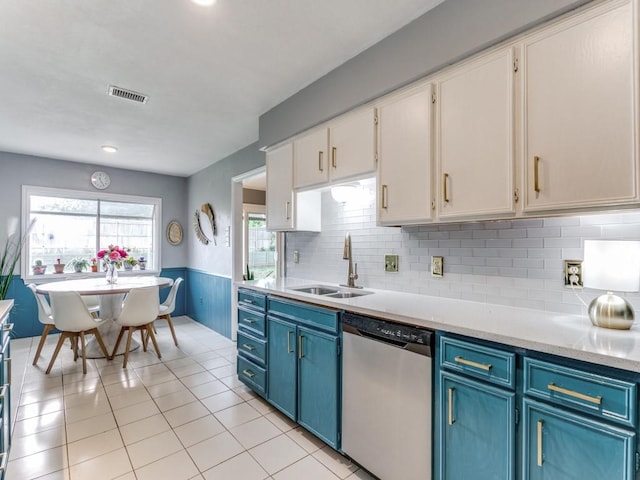 417 Merriman Dr, Highland Village, TX 75077 - kitchen with stainless steel dishwasher, blue cabinetry, light countertops, white cabinets, and a wainscoted wall