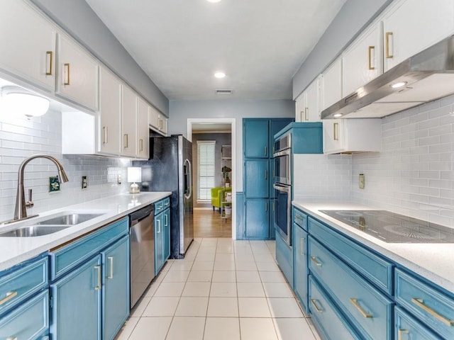 417 Merriman Dr, Highland Village, TX 75077 - kitchen featuring blue cabinetry, stainless steel appliances, wall chimney range hood, white cabinets, and light countertops