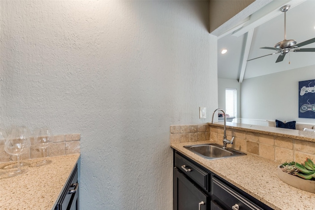 6404 Camille Ave, Dallas, TX 75252 - kitchen with a textured wall, ceiling fan, light stone counters, and dark cabinetry