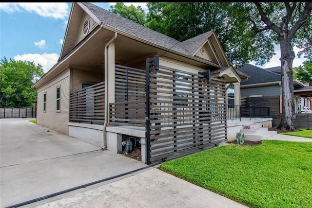 825 W 12th St, Dallas, TX 75208 - view of side of home with roof with shingles, a lawn, concrete driveway, and covered porch
