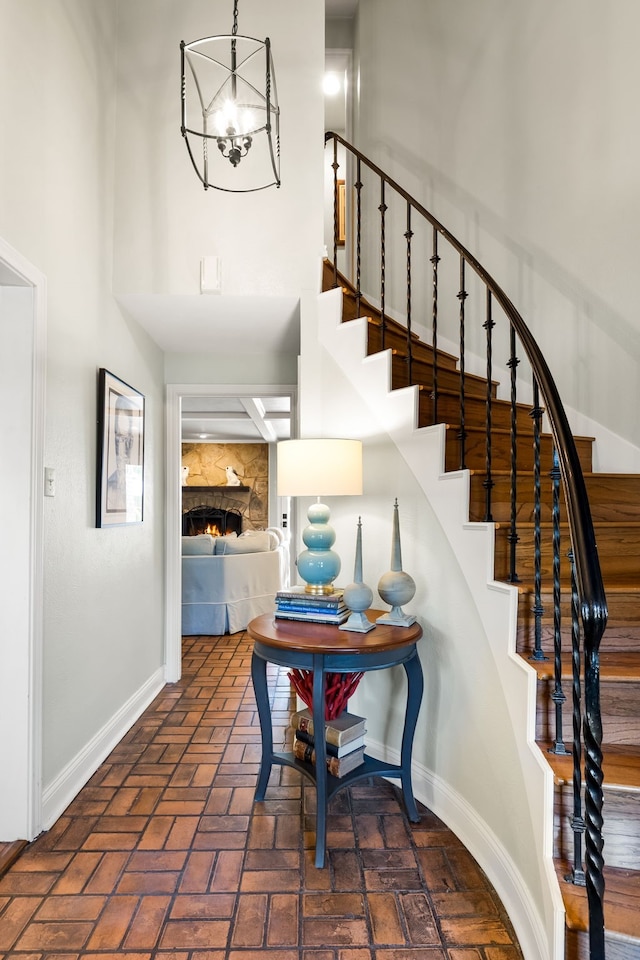 7120 Leameadow Dr, Dallas, TX 75248 - staircase with a fireplace, brick flooring, a chandelier, and a high ceiling