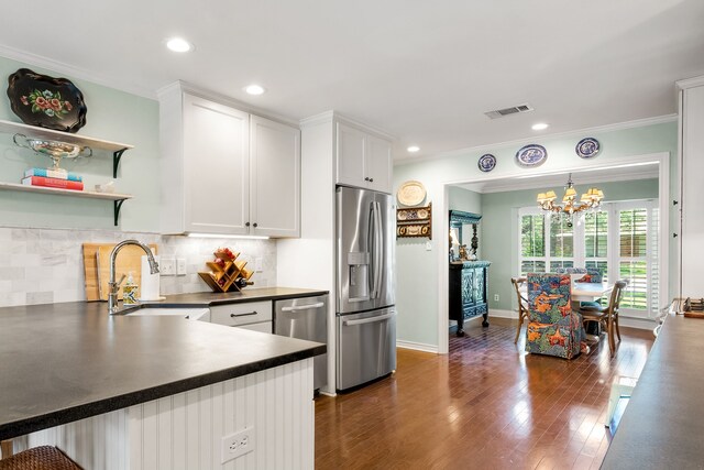 7120 Leameadow Dr, Dallas, TX 75248 - kitchen with stainless steel appliances, dark countertops, a chandelier, ornamental molding, and white cabinets
