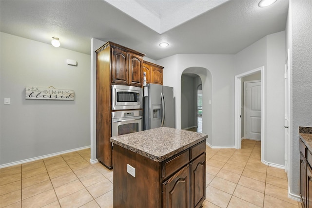 14049 Wrangler Way, Haslet, TX 76052 - kitchen with appliances with stainless steel finishes, arched walkways, light tile patterned flooring, a kitchen island, and recessed lighting