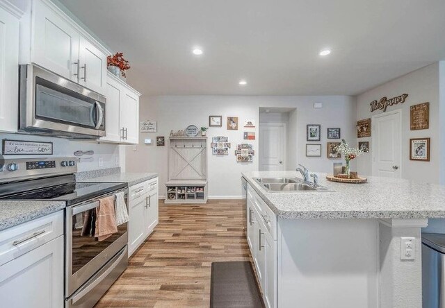 421 Atmore St, Azle, TX 76020 - kitchen featuring stainless steel appliances, white cabinets, a kitchen island with sink, light wood-style floors, and recessed lighting