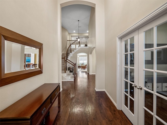 7804 Rocky Mountain Ln, Mckinney, TX 75070 - hallway with arched walkways, dark wood-style flooring, stairs, a towering ceiling, and french doors
