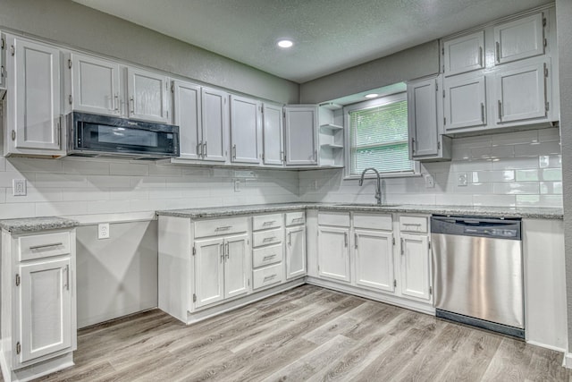 1112 Leyenda Dr, Mesquite, TX 75149 - kitchen with stainless steel dishwasher, black microwave, a textured ceiling, light wood-type flooring, and white cabinetry
