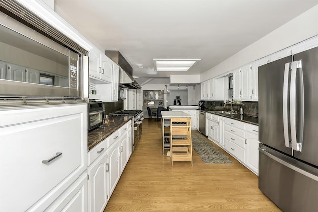2425 Northgate Dr W, Irving, TX 75062 - kitchen with appliances with stainless steel finishes, white cabinetry, light wood-style flooring, and tasteful backsplash