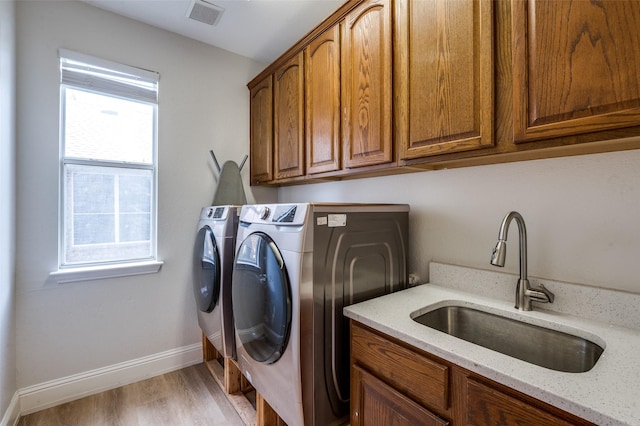 1404 Settlers Ct, Allen, TX 75002 - laundry room featuring washing machine and clothes dryer, cabinet space, healthy amount of natural light, and light wood-style floors