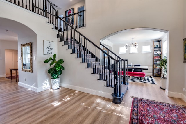 1404 Settlers Ct, Allen, TX 75002 - staircase with wood finished floors, arched walkways, a chandelier, and a high ceiling