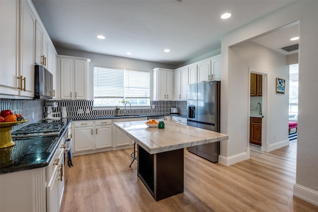 1404 Settlers Ct, Allen, TX 75002 - kitchen with appliances with stainless steel finishes, light wood-style flooring, backsplash, white cabinetry, and recessed lighting