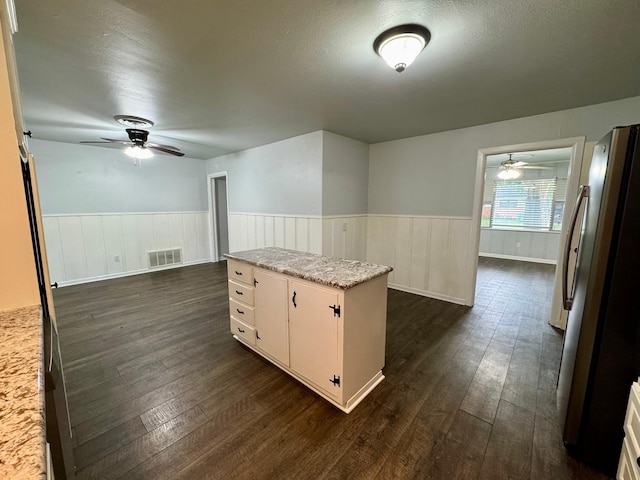 701 N Joyce St, Waco, TX 76705 - kitchen featuring freestanding refrigerator, a ceiling fan, dark wood finished floors, wainscoting, and white cabinetry
