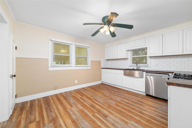 701 S Austin St, De Leon, TX 76444 - kitchen featuring stainless steel dishwasher, decorative backsplash, light wood-style flooring, and white cabinetry