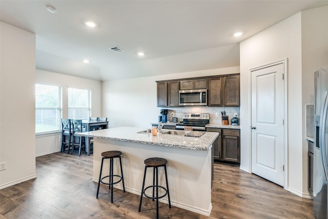 706 Meadow Creek Ln, Josephine, TX 75189 - kitchen featuring appliances with stainless steel finishes, wood finished floors, a kitchen bar, dark brown cabinets, and an island with sink