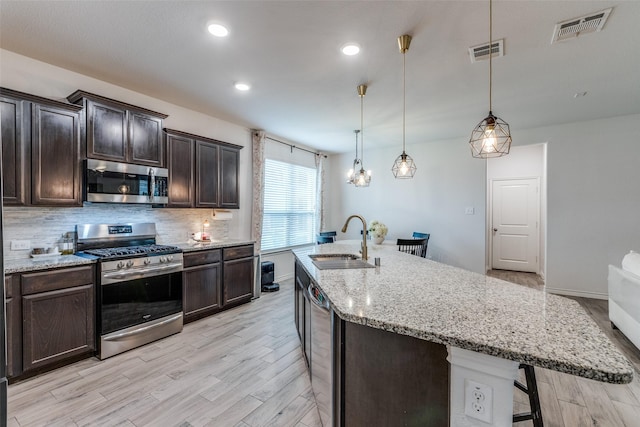 604 Grand Falls Ln, Mckinney, TX 75071 - kitchen featuring appliances with stainless steel finishes, a breakfast bar, light wood-style flooring, dark brown cabinets, and backsplash