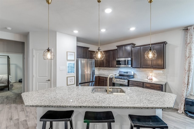 604 Grand Falls Ln, Mckinney, TX 75071 - kitchen featuring appliances with stainless steel finishes, dark brown cabinets, a kitchen bar, backsplash, and recessed lighting