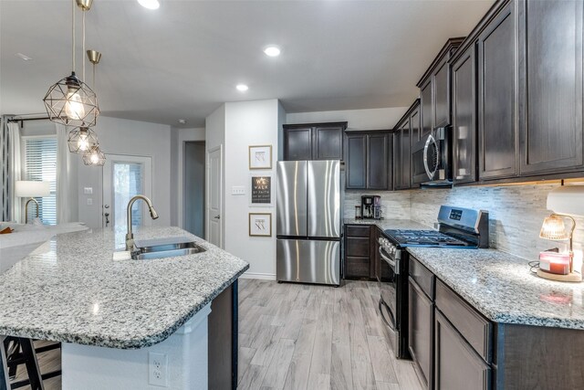 604 Grand Falls Ln, Mckinney, TX 75071 - kitchen with appliances with stainless steel finishes, light stone countertops, tasteful backsplash, light wood-style flooring, and a large island