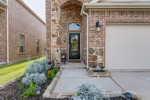 604 Grand Falls Ln, Mckinney, TX 75071 - property entrance with brick siding, an attached garage, driveway, and stone siding