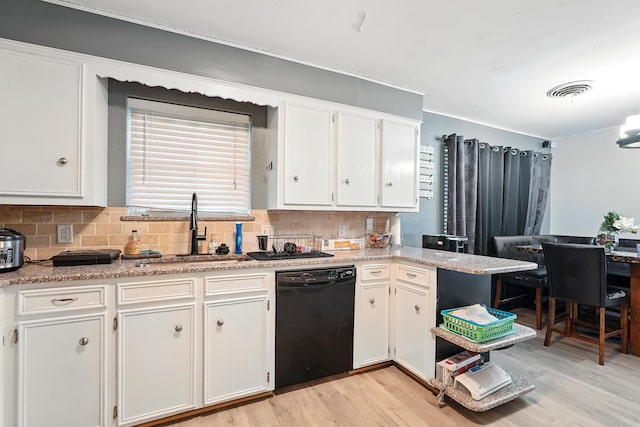 3102 Primrose Dr, Abilene, TX 79606 - kitchen with black dishwasher, light wood-style flooring, white cabinets, decorative backsplash, and light countertops