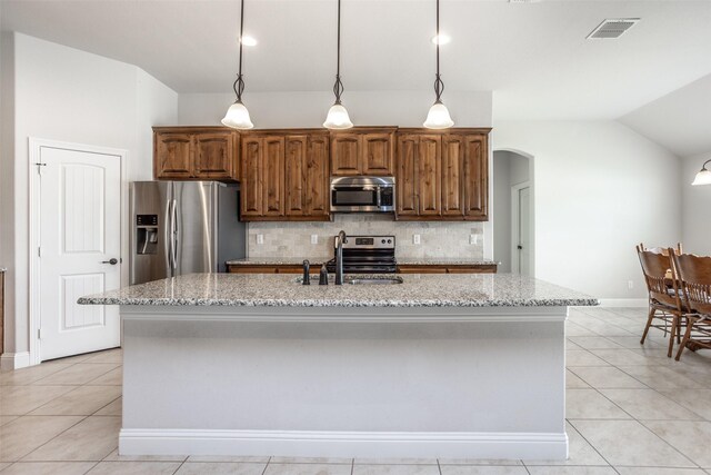 103 Loving Trl, Justin, TX 76247 - kitchen with appliances with stainless steel finishes, lofted ceiling, arched walkways, tasteful backsplash, and light tile patterned floors
