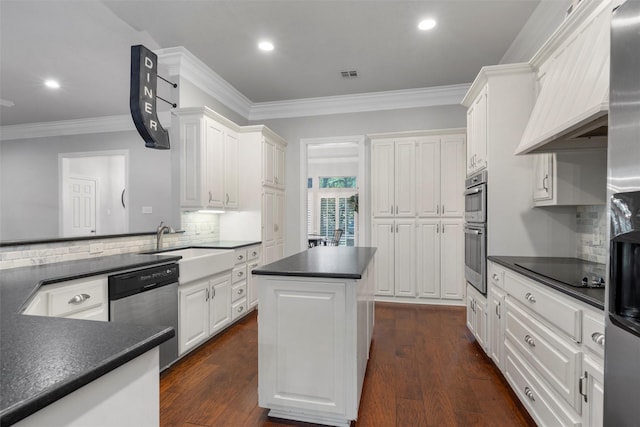 9604 Oak Springs Dr, Woodway, TX 76712 - kitchen with stainless steel appliances, dark countertops, ornamental molding, custom range hood, and white cabinets
