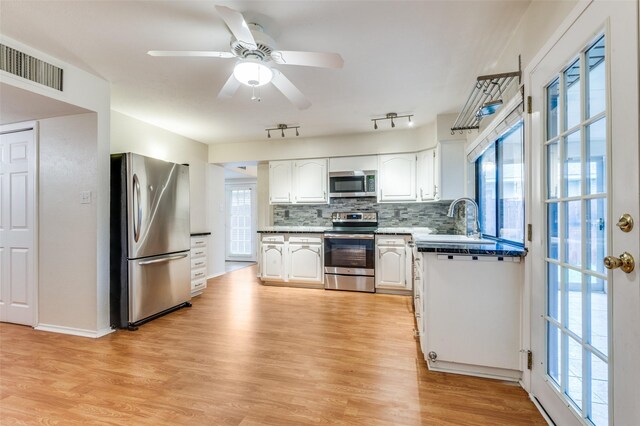 308 Woodhurst Pl, Coppell, TX 75019 - kitchen featuring appliances with stainless steel finishes, decorative backsplash, white cabinetry, light wood-style flooring, and plenty of natural light