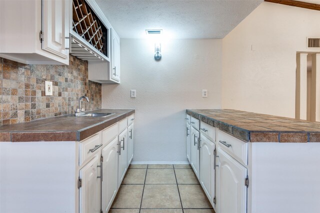 308 Woodhurst Pl, Coppell, TX 75019 - kitchen with backsplash, white cabinetry, a peninsula, a textured ceiling, and light tile patterned floors