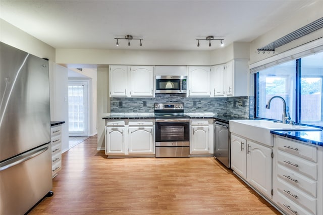 308 Woodhurst Pl, Coppell, TX 75019 - kitchen featuring appliances with stainless steel finishes, white cabinetry, light wood-type flooring, and decorative backsplash