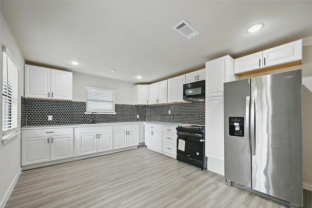 8620 Greenmound Ave, Dallas, TX 75227 - kitchen featuring black appliances, light wood-style flooring, white cabinetry, tasteful backsplash, and recessed lighting