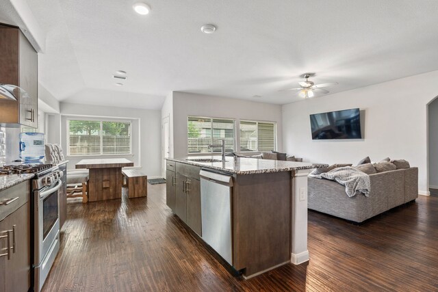 1108 Sheldon Dr, Anna, TX 75409 - kitchen with appliances with stainless steel finishes, dark wood-style flooring, light stone countertops, a ceiling fan, and an island with sink