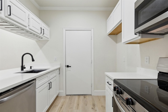 7340 Skillman St Unit 107, Dallas, TX 75231 - kitchen featuring appliances with stainless steel finishes, light wood finished floors, light countertops, white cabinetry, and ornamental molding