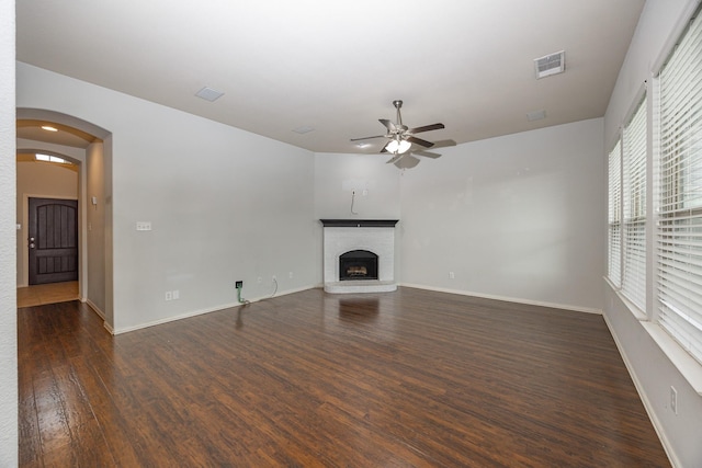 2111 Rains County Rd, Forney, TX 75126 - unfurnished living room featuring a ceiling fan, dark wood-style flooring, a brick fireplace, and arched walkways